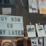 a store window with a sign that says buy now or cry later