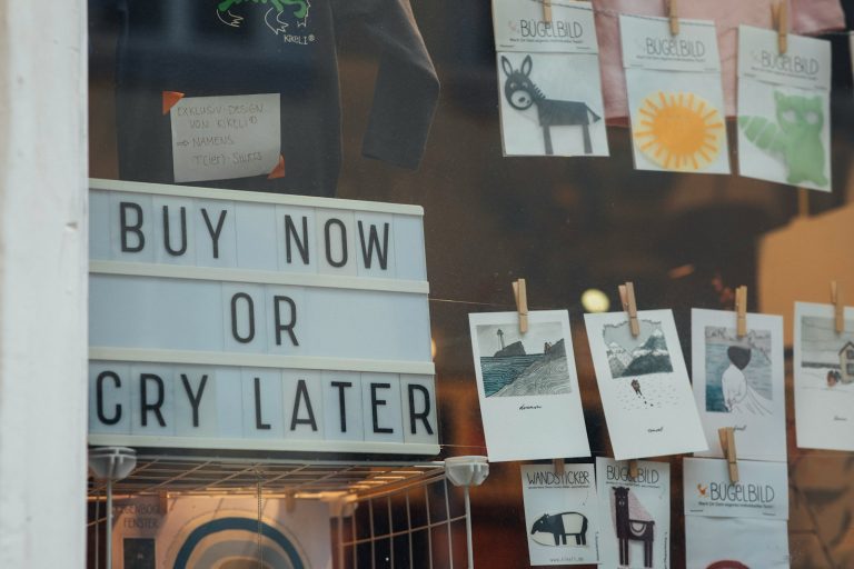 a store window with a sign that says buy now or cry later